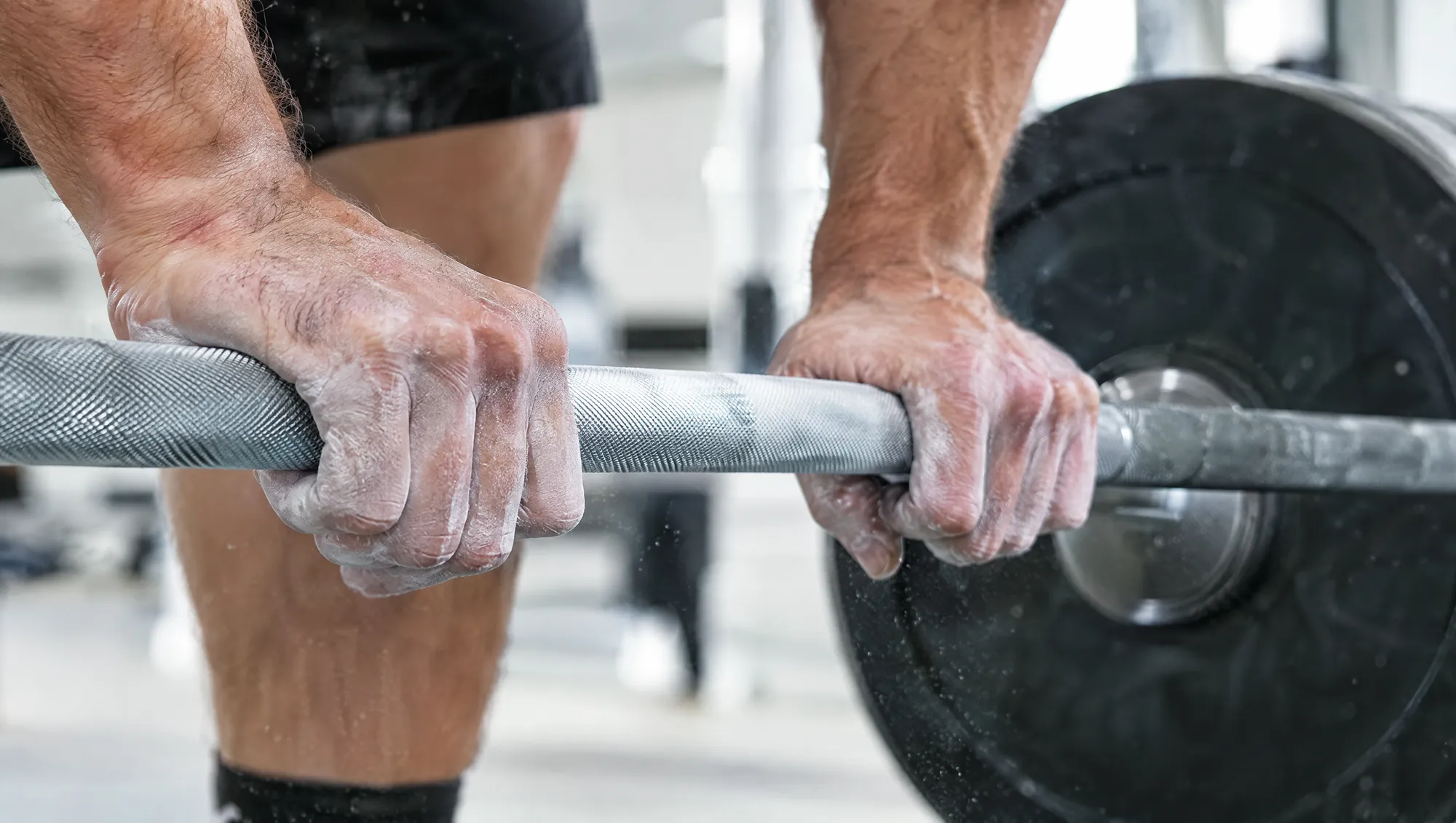 Chalked hands gripping a barbell