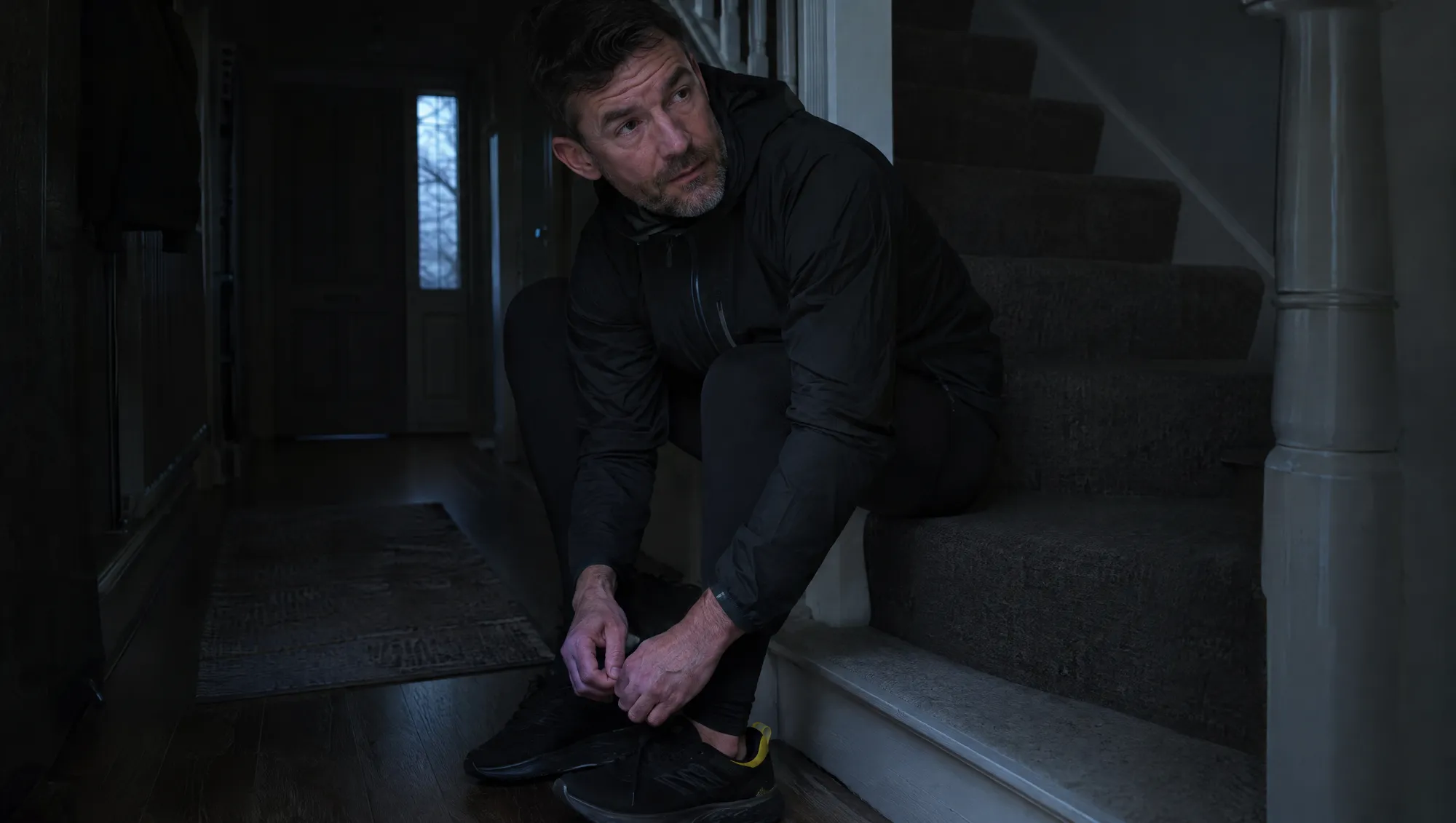A man lacing his running shoes before dawn